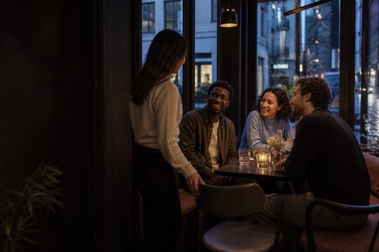 A small group welcoming someone new at a city cafe